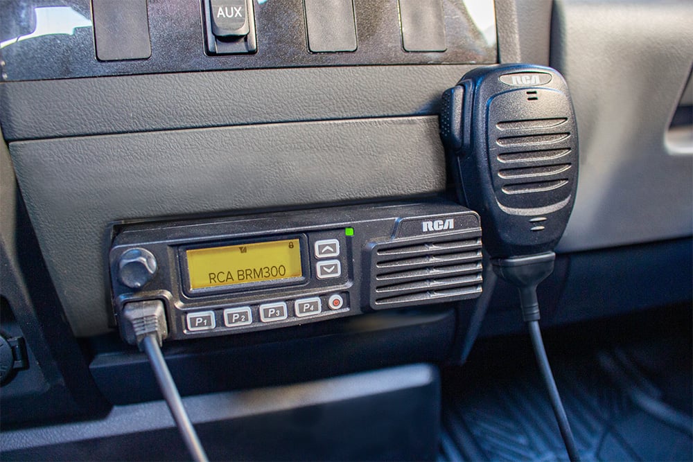 An RCA BRM300D mobile two-way radio is mounted to a vehicle's center console.